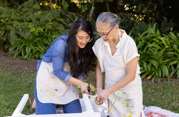 Painting furniture together, asian granddaughter and grandmother enjoying outdoor diy project in garden. crafting, teamwork, bonding, creativity, home improvement, leisure